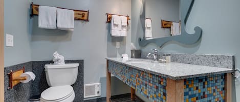 Un baño con inodoro, lavabo, espejo y salpicadero de azulejos.