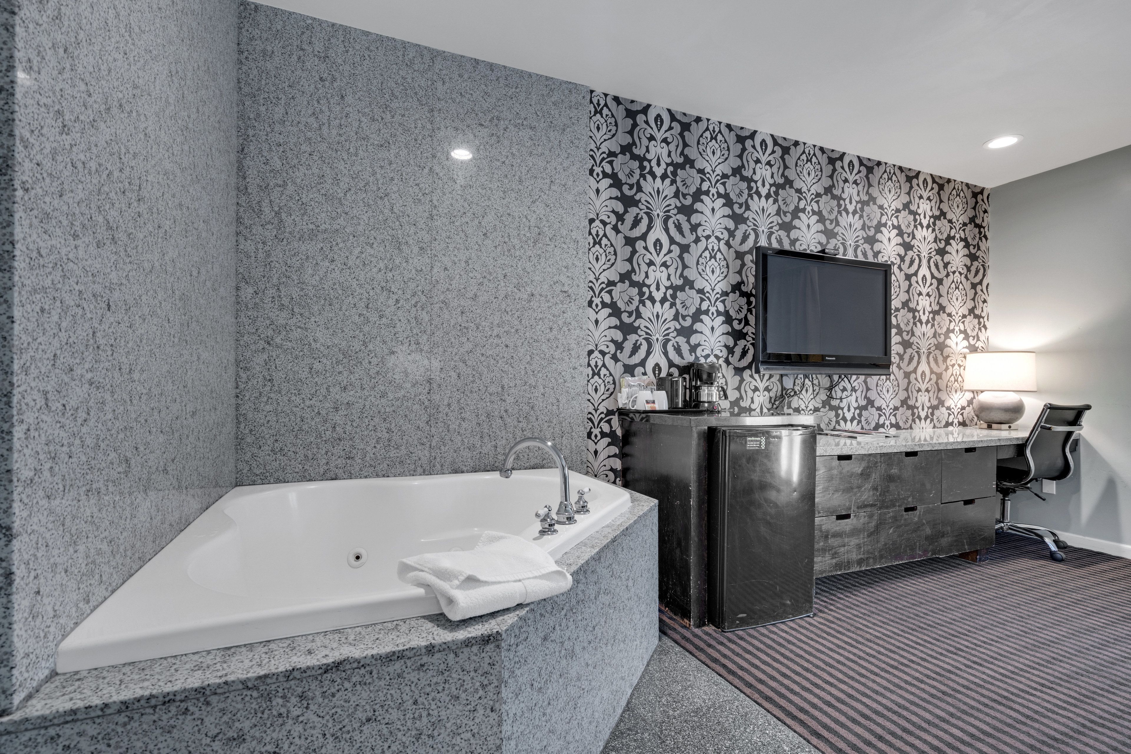 A modern bathroom with a freestanding bathtub, a vanity with a mirror, and a flat-screen TV mounted on the wall.