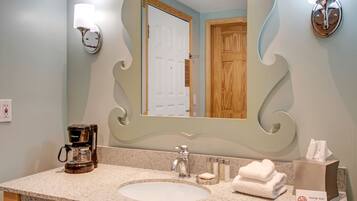 A bathroom with a large mirror, a coffee maker, and a towel dispenser.
