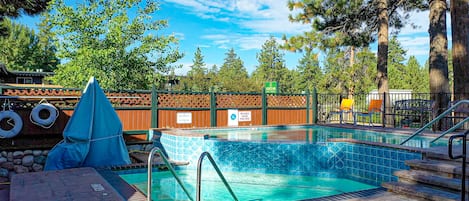 A swimming pool with a tiled edge, surrounded by a wooden fence, and a lifeguard chair.