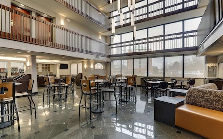 A spacious indoor area with multiple seating arrangements, including tables and chairs, and a central sofa area.