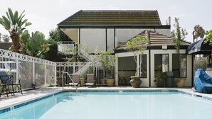 A swimming pool with a covered patio area, outdoor seating, and a small garden. - Alamo Inn & Suites (Anaheim)