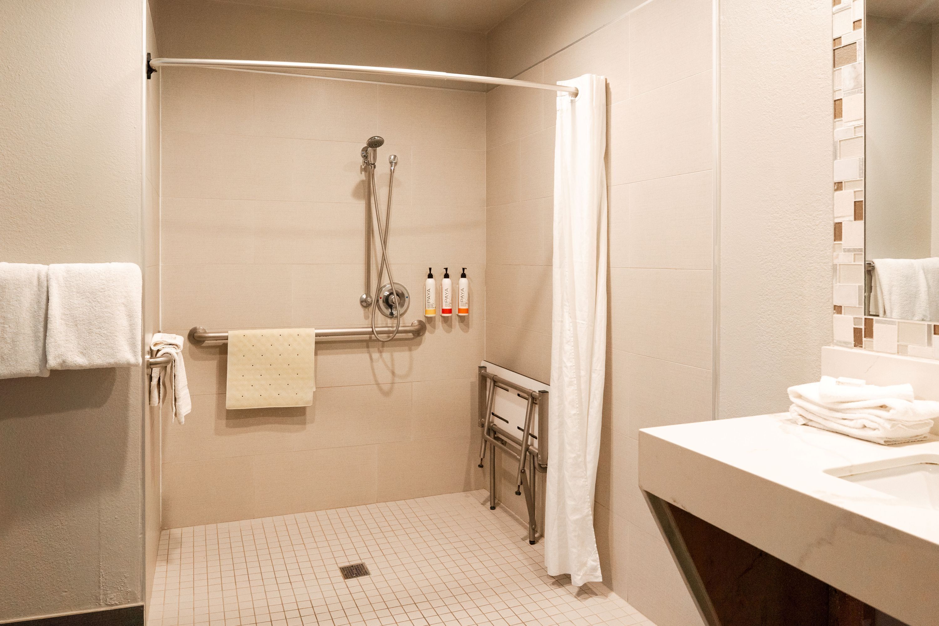 A bathroom with a shower, a towel rack, and a sink.