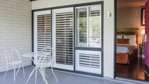 A room with a bed, a table with chairs, and a window with blinds. - Alamo Inn & Suites (Anaheim)