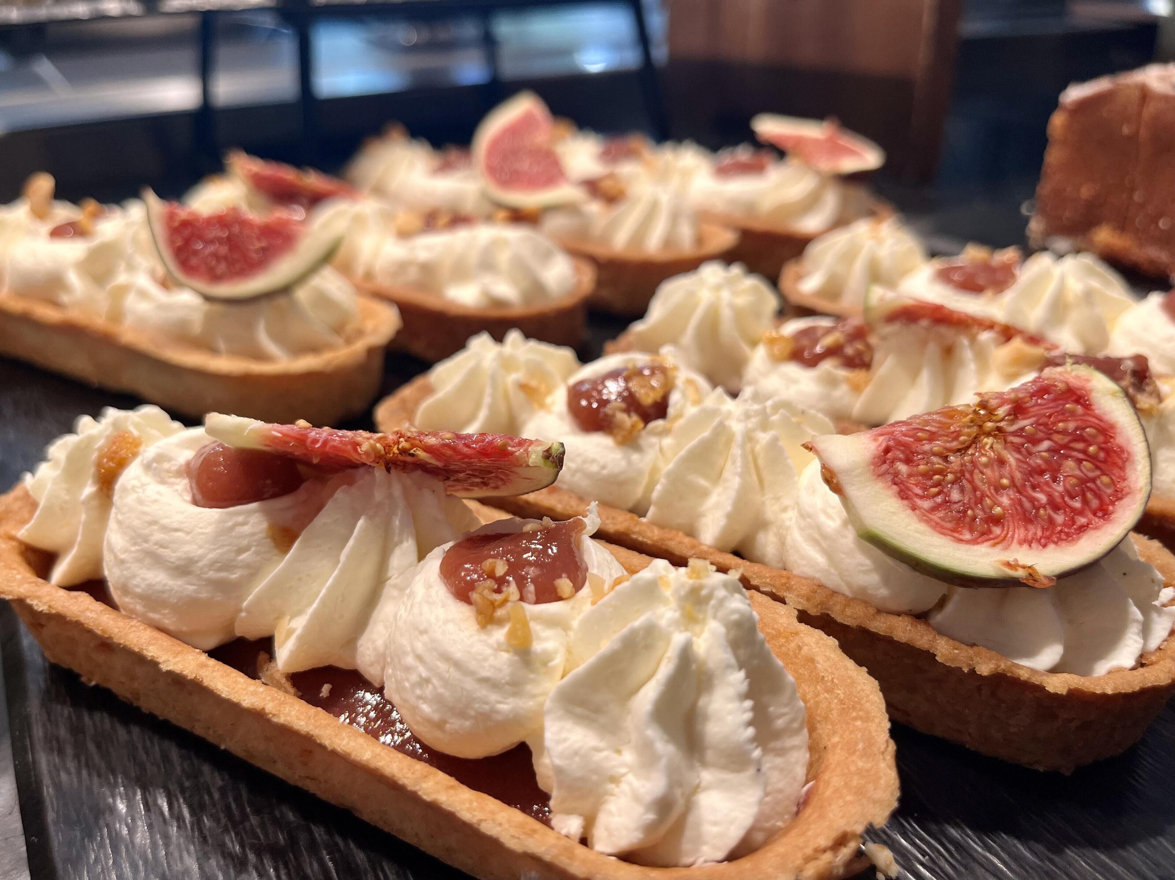 Eine Dessertauslage mit Tartlets, bedeckt mit Schlagsahne und Feigen.