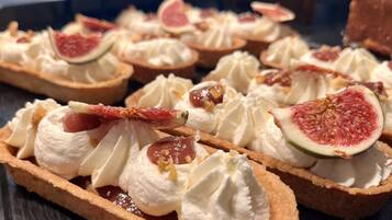 A dessert display with tarts topped with whipped cream and figs.