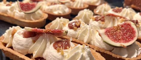 A dessert display with tarts topped with whipped cream and figs.