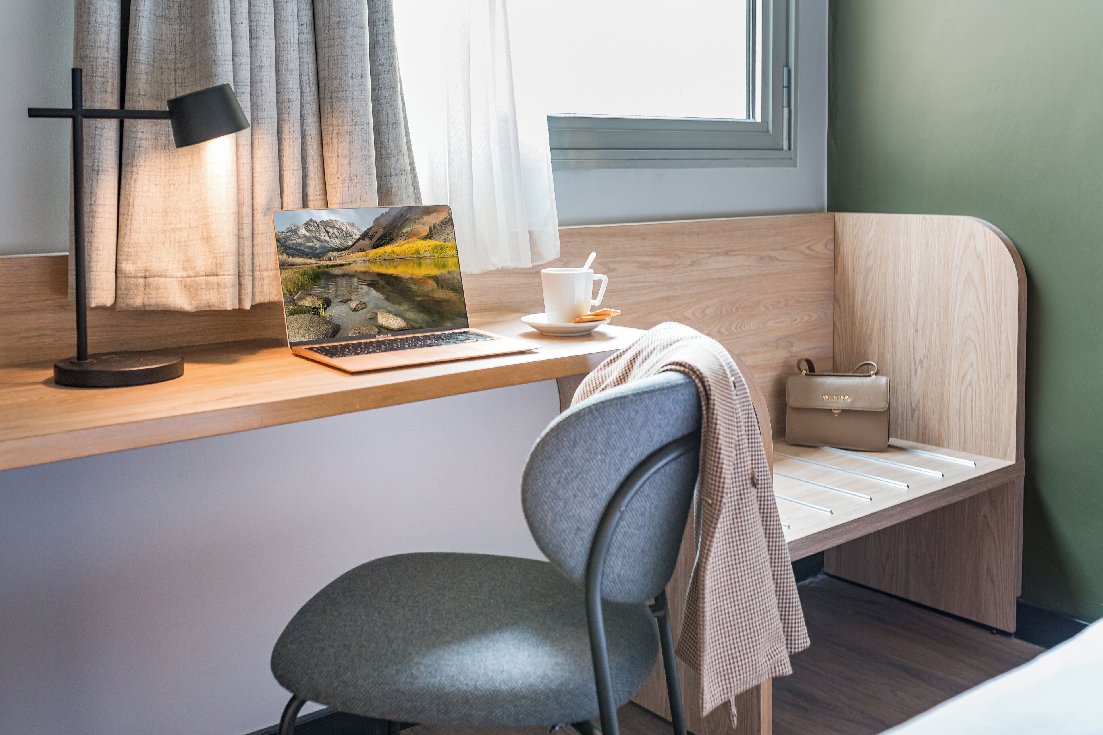 Una habitación moderna con un escritorio de madera, una computadora portátil, una taza y una silla.