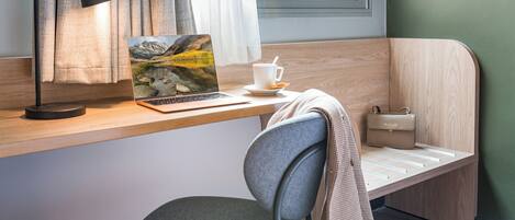 Una habitación moderna con un escritorio de madera, una computadora portátil, una taza y una silla.