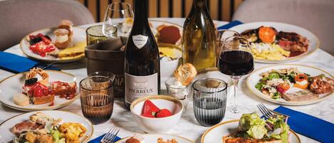 A dining table with various dishes, wine bottles, and glasses.