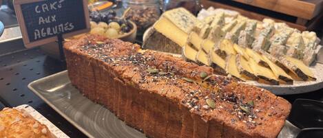 A bakery display with various baked goods including a loaf of cake, assorted cheeses, and pastries.
