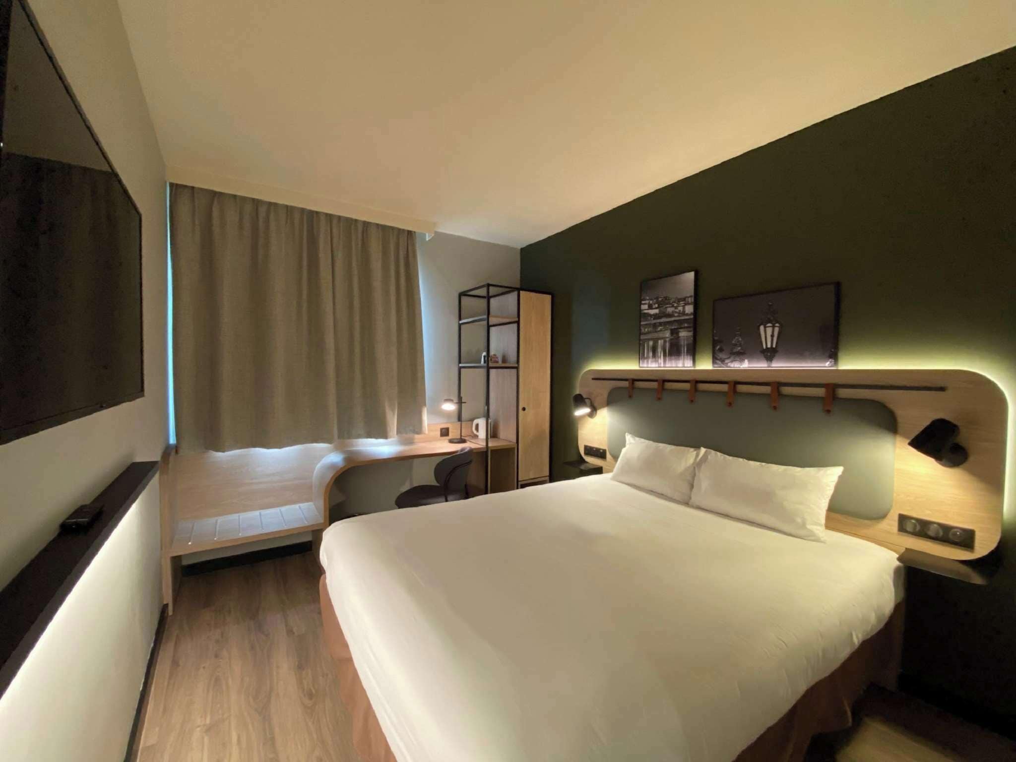 Una habitación de hotel con una cama grande, un escritorio, una silla, un armario y un televisor.