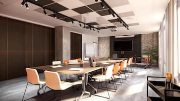 Una sala de conferencias moderna con una mesa larga, sillas blancas y anaranjadas, una pantalla grande y una pizarra.