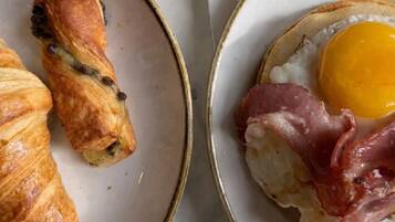 A plate with a croissant and a fried egg with bacon.
