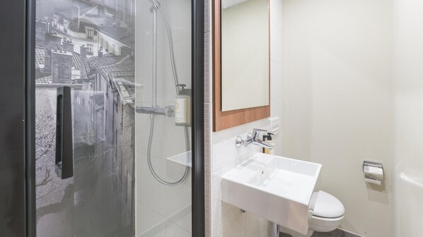 A modern bathroom with a glass shower enclosure, a white sink, and a toilet. - Campanile PRIME - Lyon Centre - Gare Perrache (Lyon)