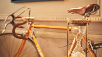 An hourglass on a wooden table with a bicycle in the background.