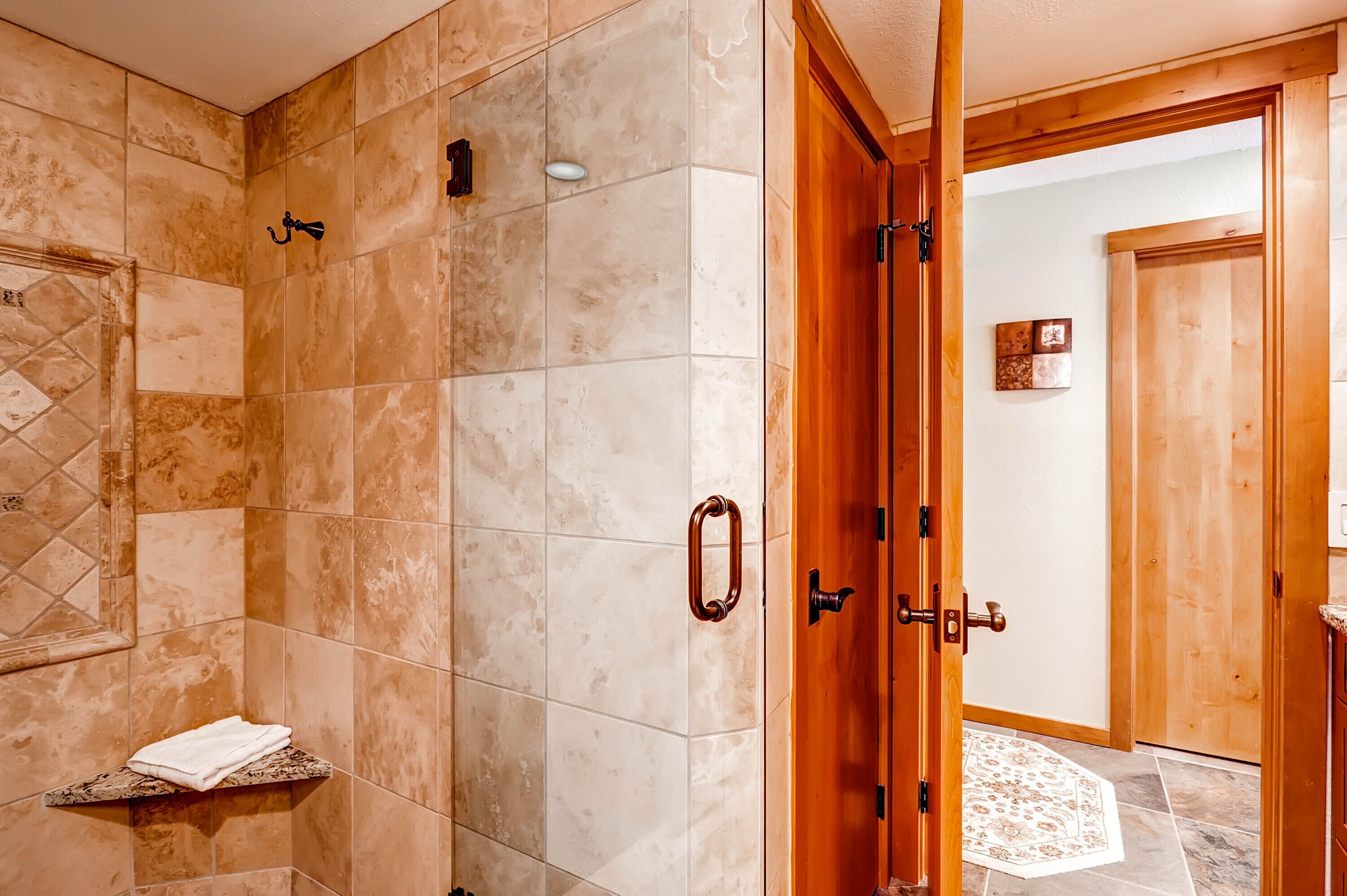 A bathroom with beige tiles, a wooden door, and a towel rack.