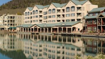A multi-story hotel with balconies, a dock, and a calm lake in the foreground.