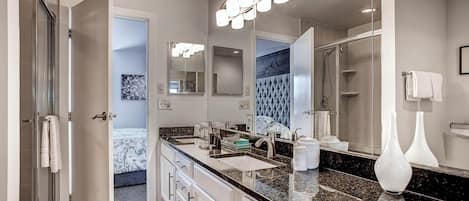 A modern bathroom with a large mirror, dual sinks, and a shower area.
