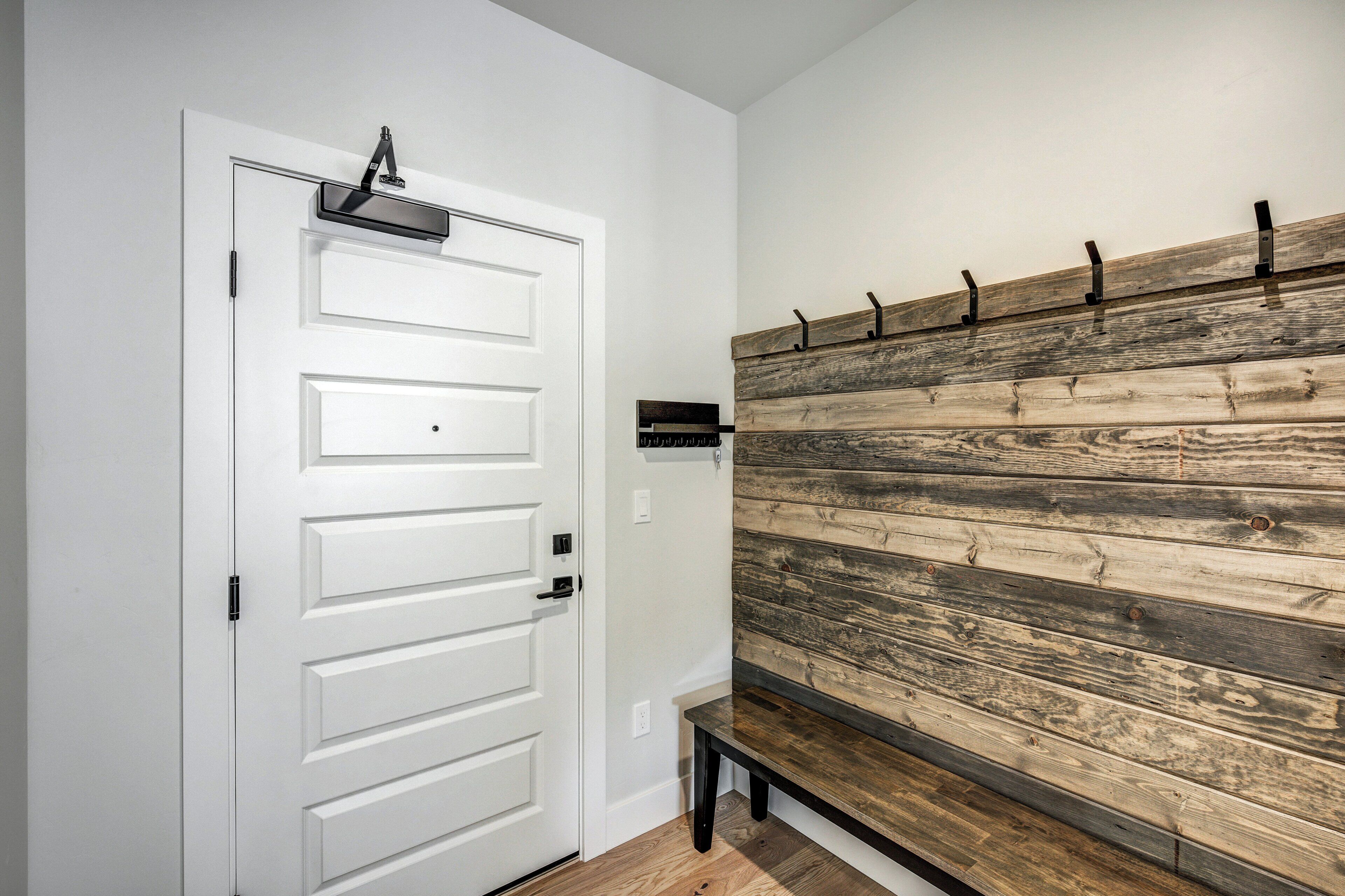 A white door with a black handle, a wooden wall with a rustic finish, and a bench against the wall.