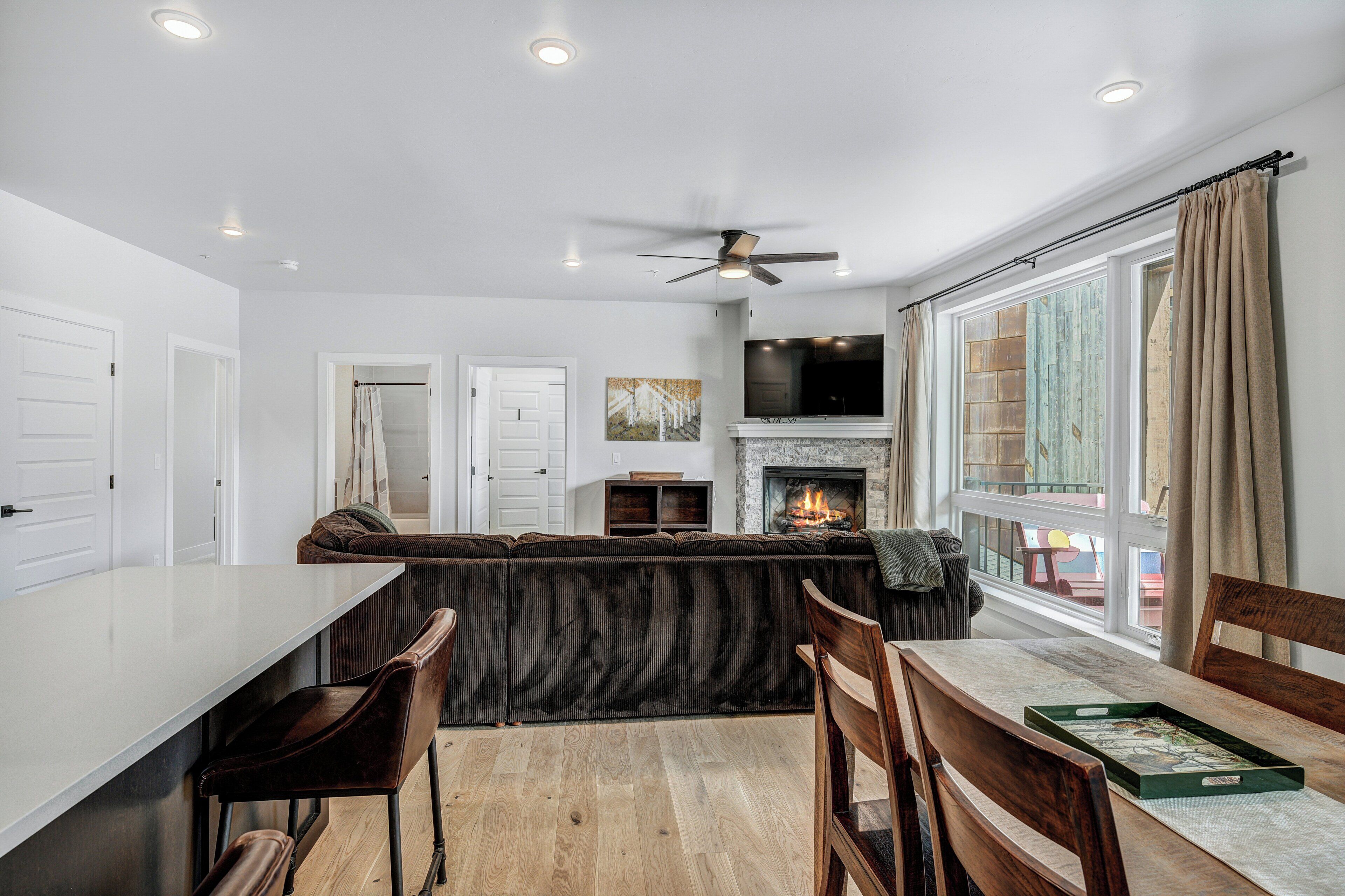 A modern kitchen with a central island, a dining area with wooden chairs, and a fireplace.