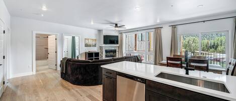 Une cuisine moderne équipée d’un lave-vaisselle, d’un grand îlot central et d’un coin repas offrant une vue sur l’extérieur.