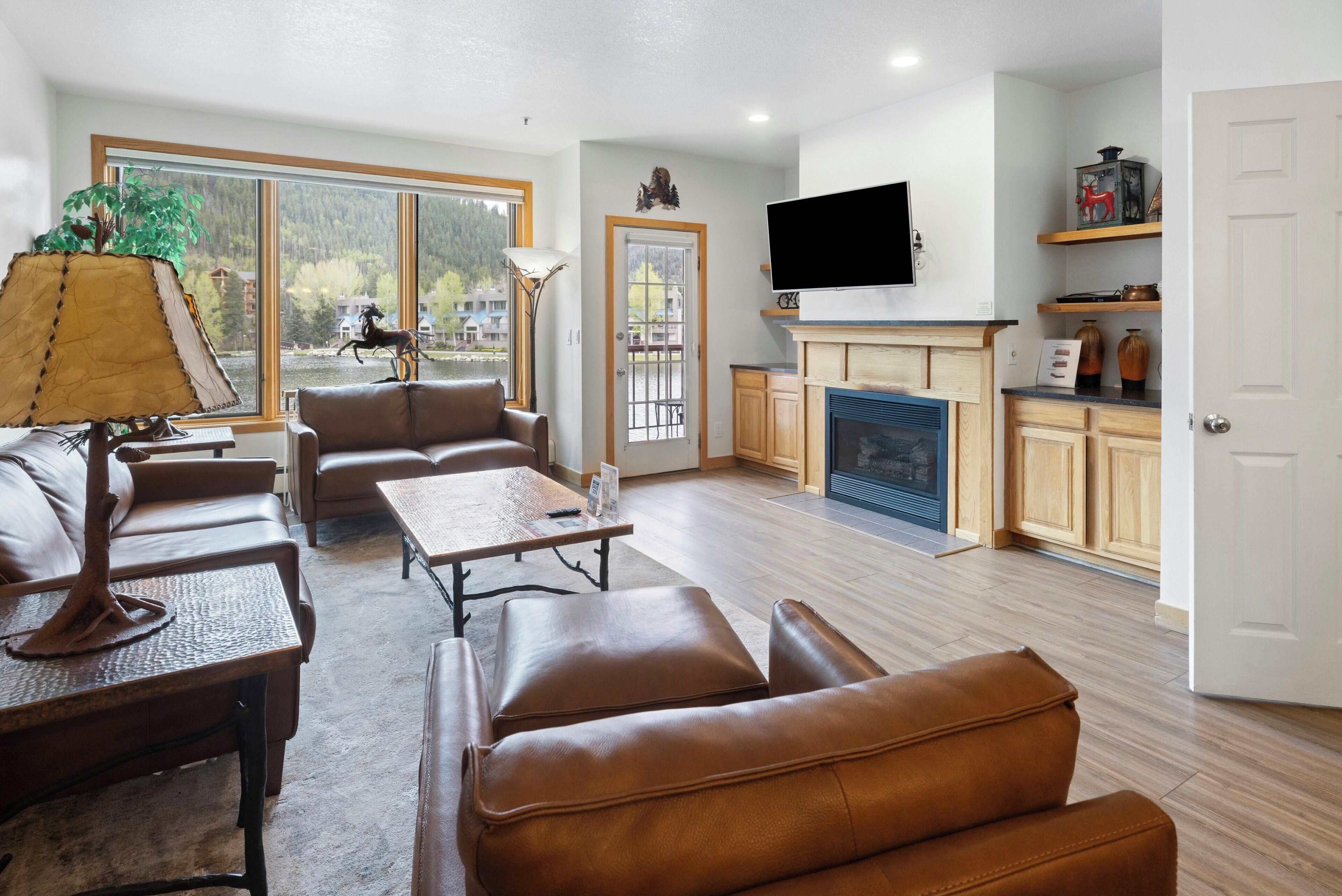 A spacious living room with leather sofas, a fireplace, and a television mounted above it.