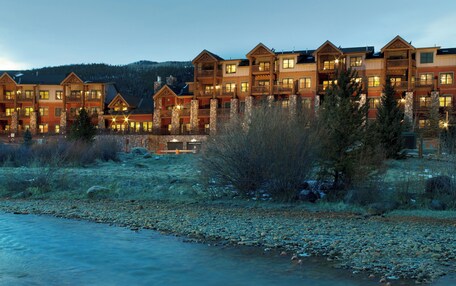 A multi-story hotel with balconies and a river in the foreground.