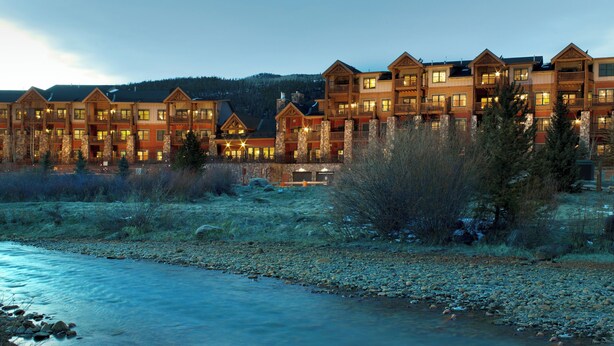A multi-story hotel with balconies and a river in the foreground. - Mountain House, A Vail Resorts Property (Keystone)