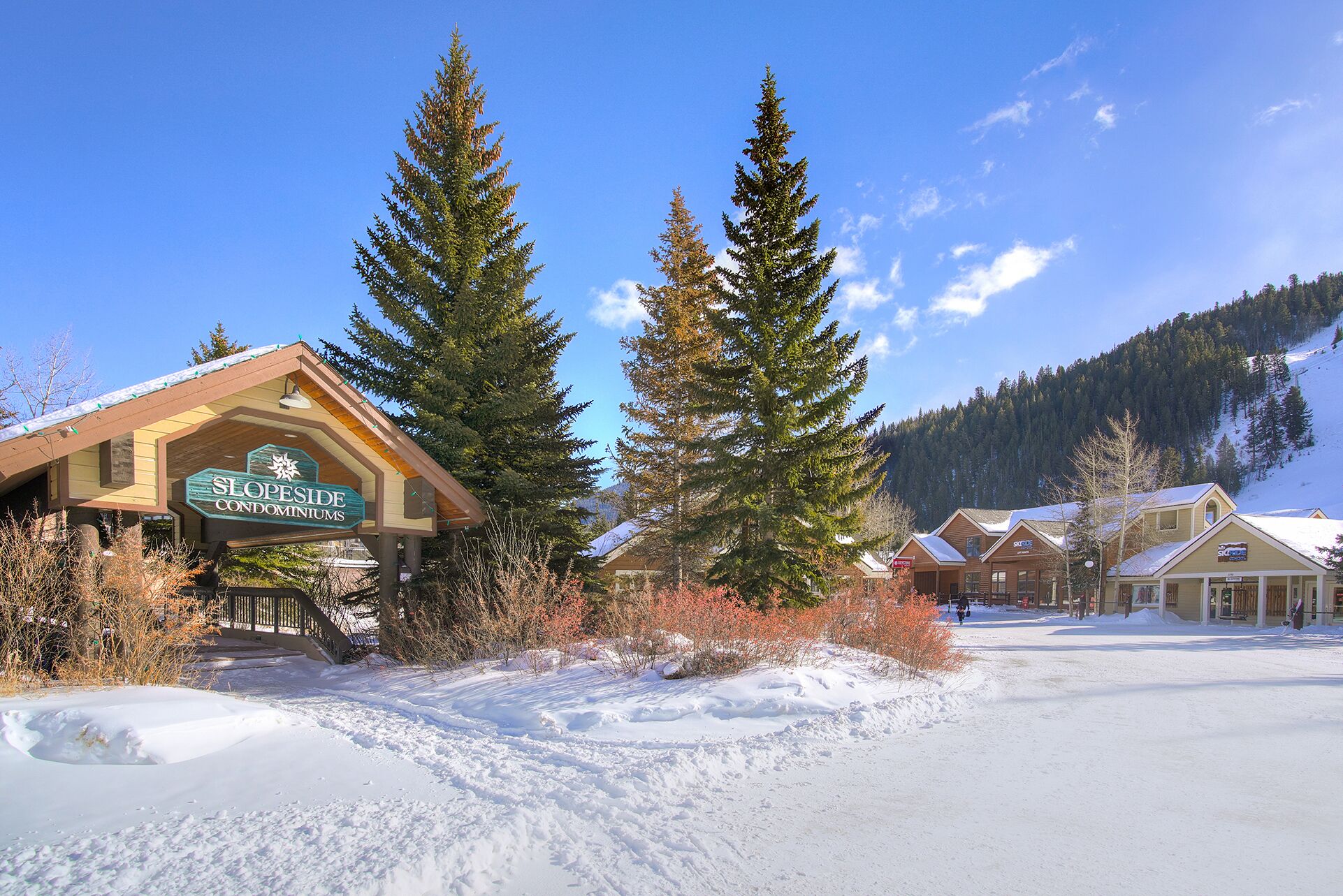 A lodge with a sign reading "SLOPESIDE CONDOMINIUMS" and a snow-covered landscape.