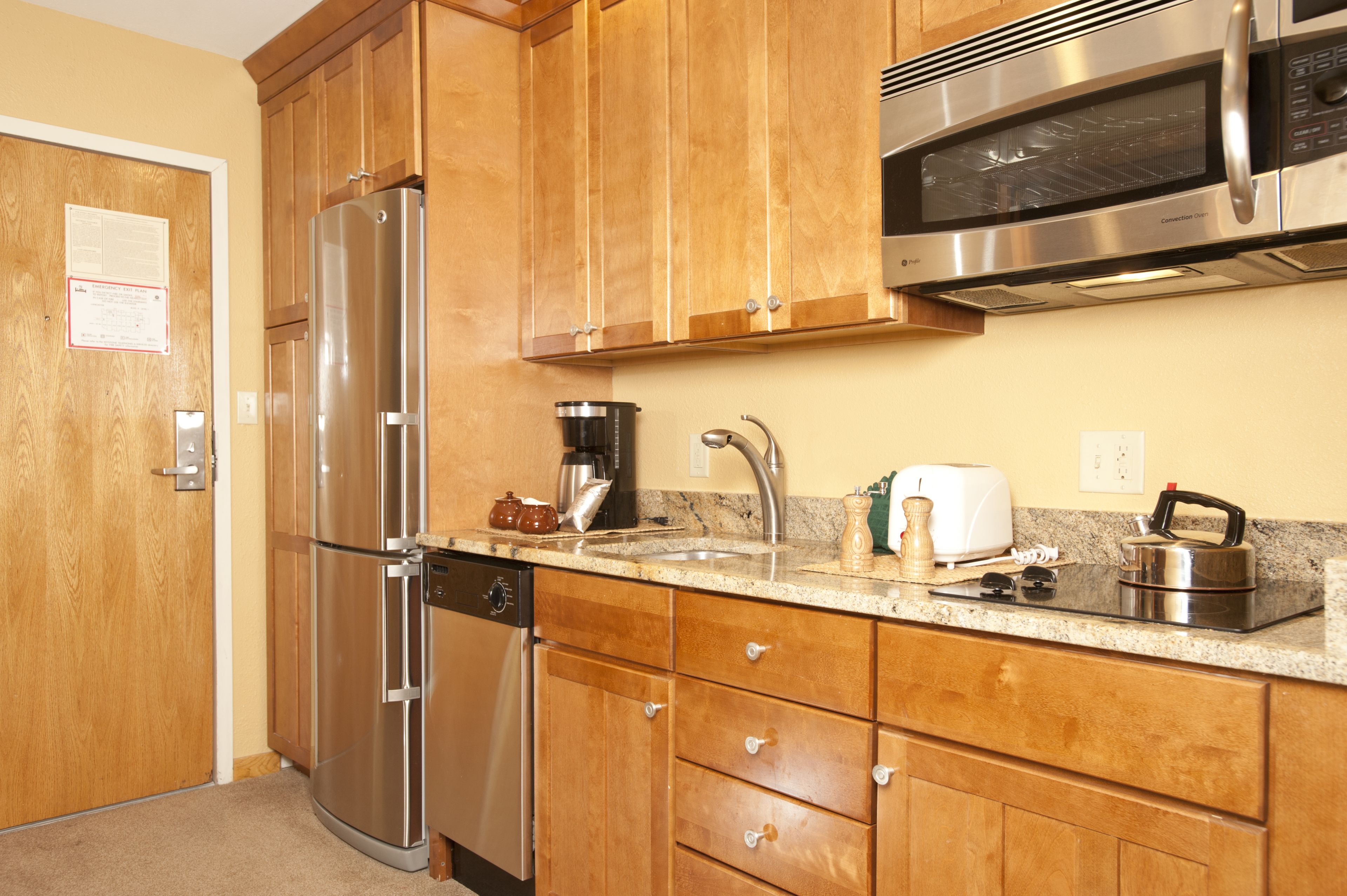 A kitchen with wooden cabinets, stainless steel appliances, a sink, and a countertop with various items.