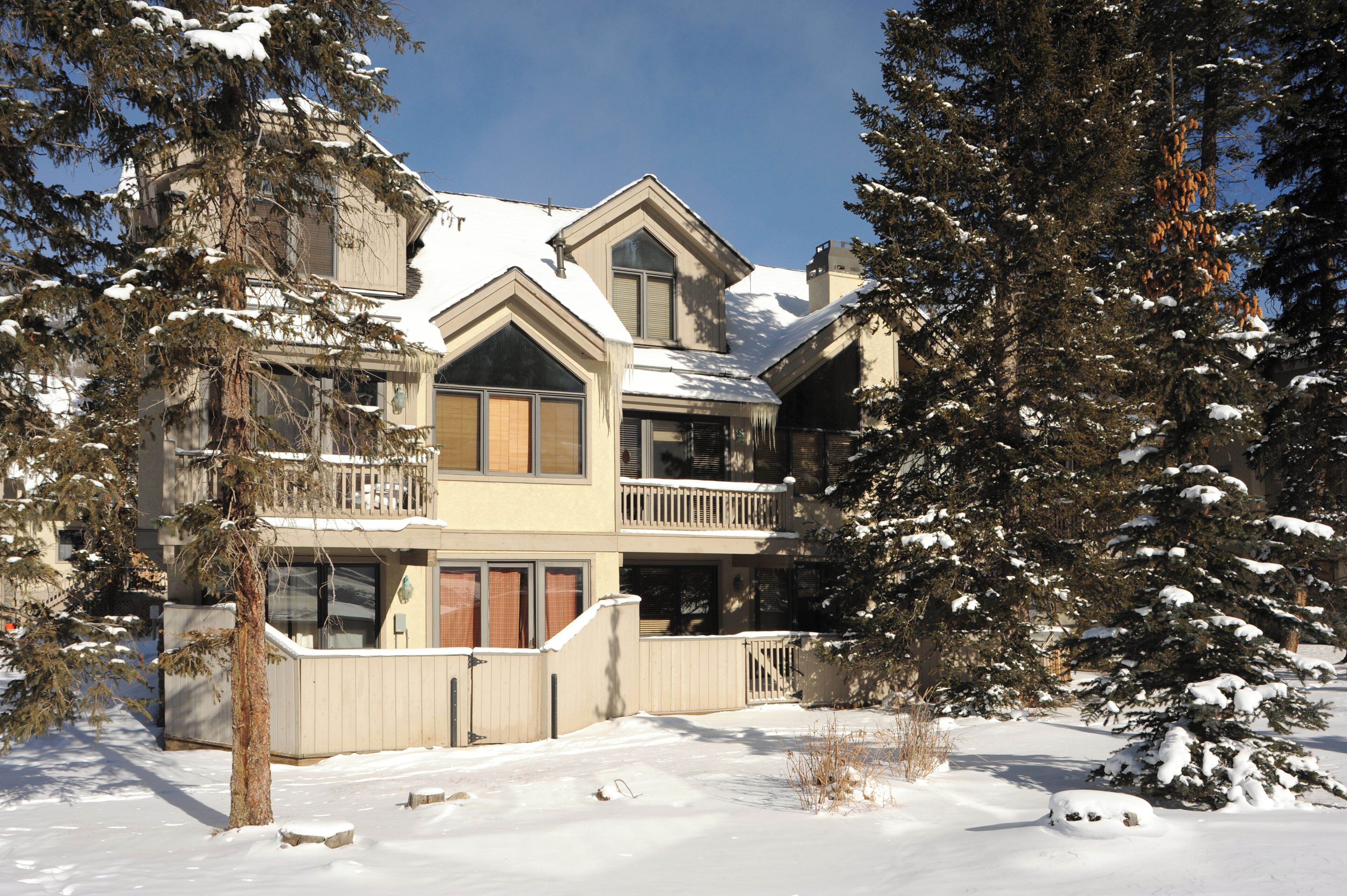 A large, multi-story building with a snow-covered roof and surrounding trees.