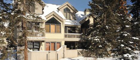 A large, multi-story building with a snow-covered roof and surrounding trees.