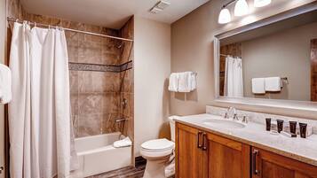 A modern bathroom with a bathtub, toilet, and vanity with a sink and mirror.