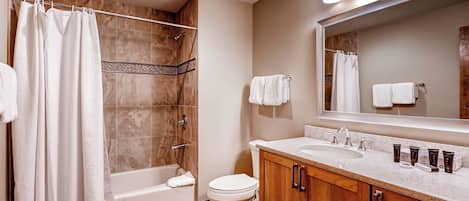 Een moderne badkamer met een bad, toilet en wastafel met een wastafelbak en spiegel.