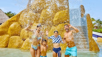 Un espace de jeux aquatiques doté d’une grande fontaine et d’une structure dorée.