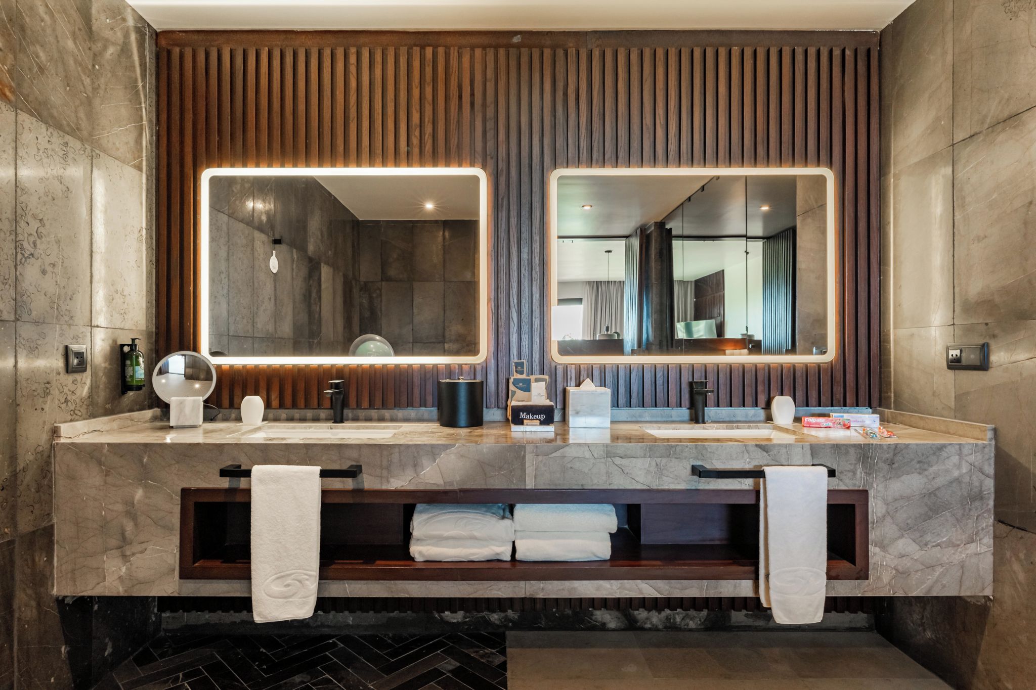 A modern bathroom with two sinks, a mirror, and a towel rack.