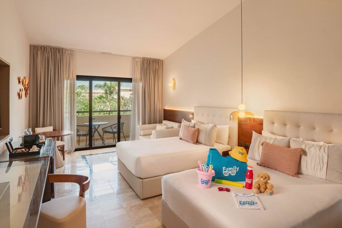 A hotel room with two beds, a desk, and a dining area.