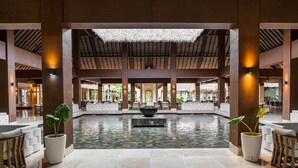 A spacious lobby with a central water feature, seating areas, and a thatched ceiling. - Grand Palladium Kantenah Resort & Spa All Inclusive (Kantenah)