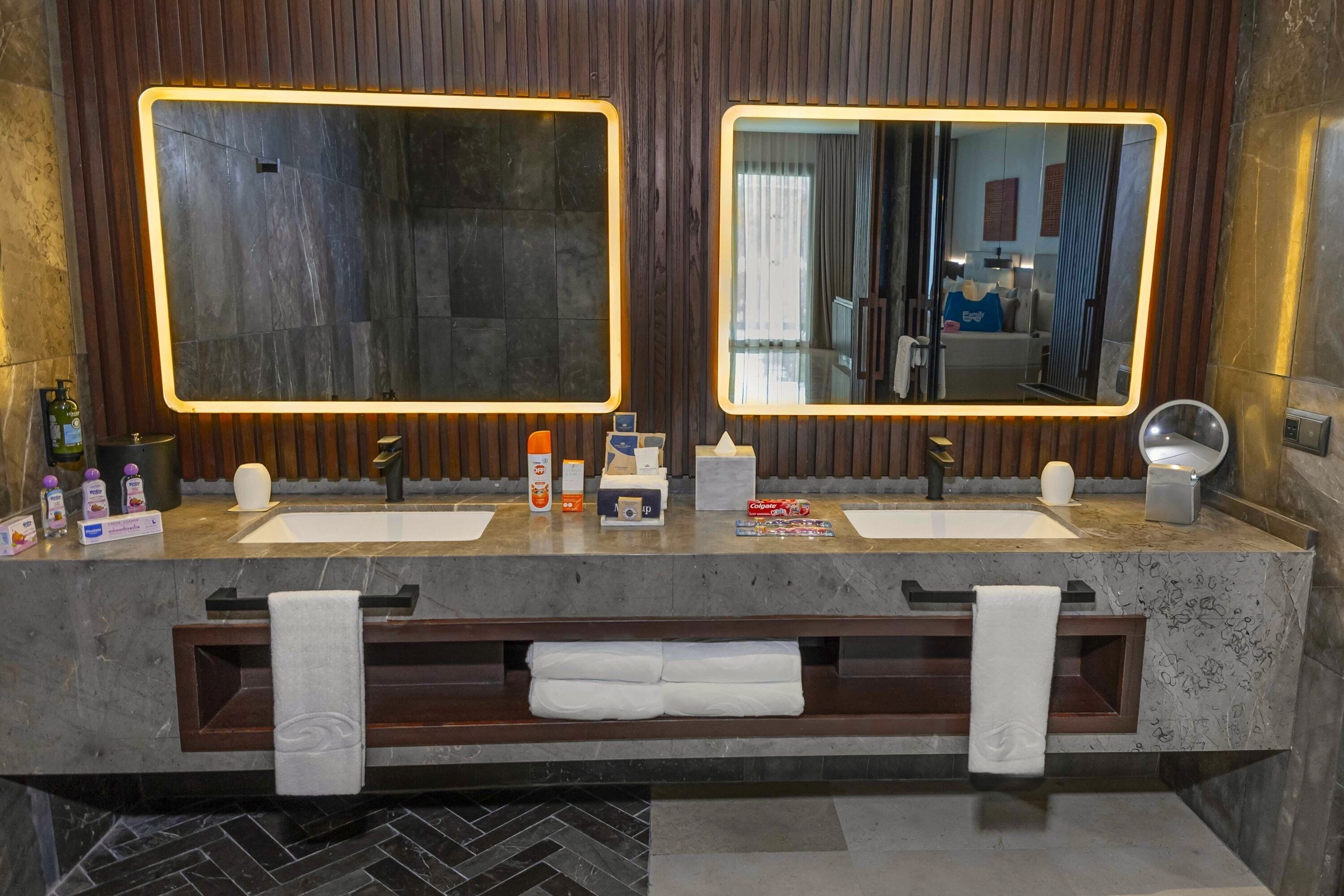 Une salle de bain moderne avec deux lavabos, un grand miroir et un meuble-lavabo avec des articles de toilette.