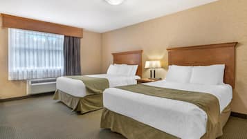 Habitación de hotel con dos camas, una ventana con cortinas, una lámpara en la mesita de noche y un equipo de aire acondicionado.
