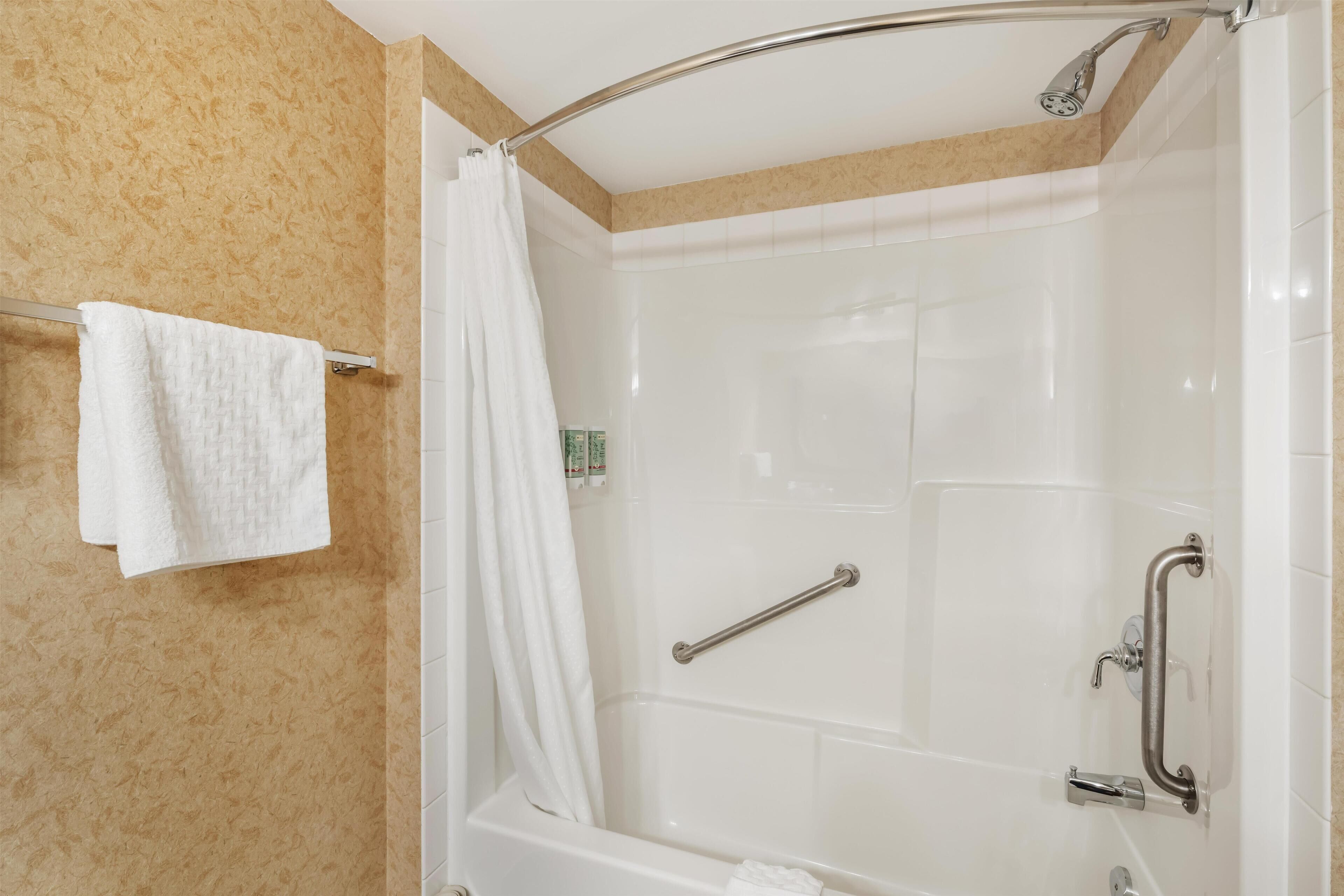 Ein modernes Badezimmer mit Badewanne, Dusche und Haltegriffen.