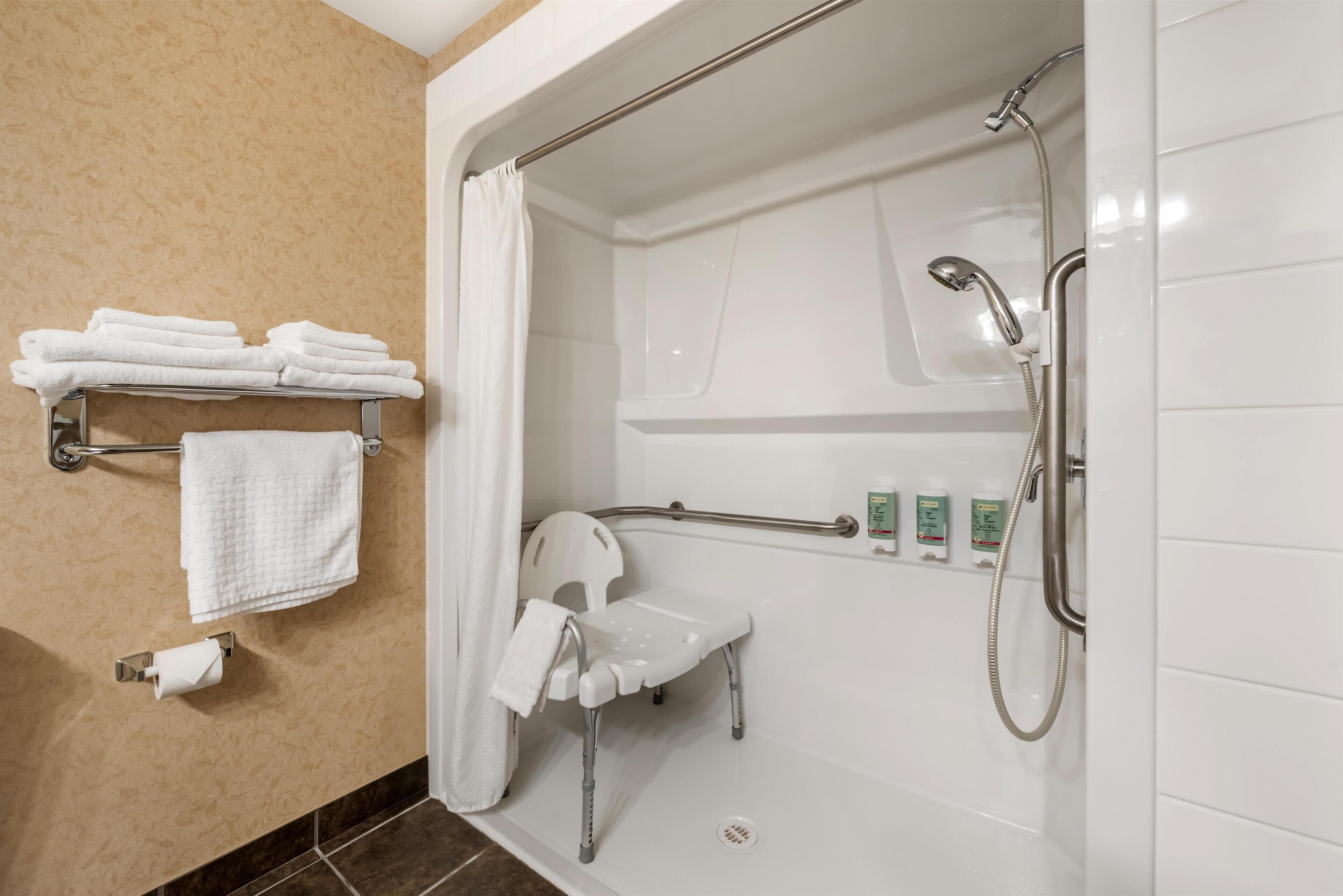 Un baño moderno con cabina de ducha, un toallero blanco y una barra de apoyo.
