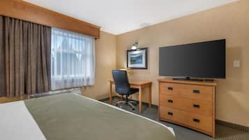 A hotel room with a bed, a desk, a chair, a television, and a dresser.