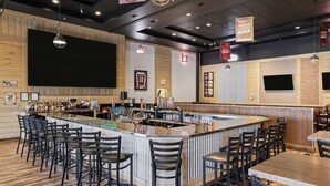 A bar area with a central island, bar stools, and a counter with a cash register. - Days Inn & Suites by Wyndham Winkler (Winkler)