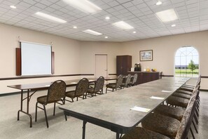 Conference room with a long table and comfortable seating, a whiteboard, and a cabinet.