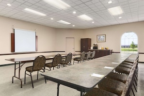 Conference room with a long table and comfortable seating, a whiteboard, and a cabinet.