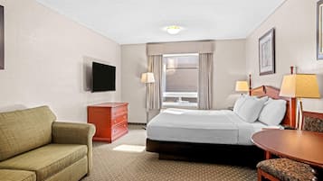 A hotel room with a bed, a sofa, a desk, and a TV.
