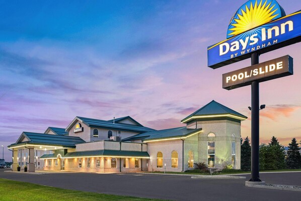 A Days Inn by Wyndham hotel with a pool and slide, featuring a modern architectural design with a prominent sign and well-lit exterior. - Days Inn & Suites by Wyndham Winkler (Winkler)