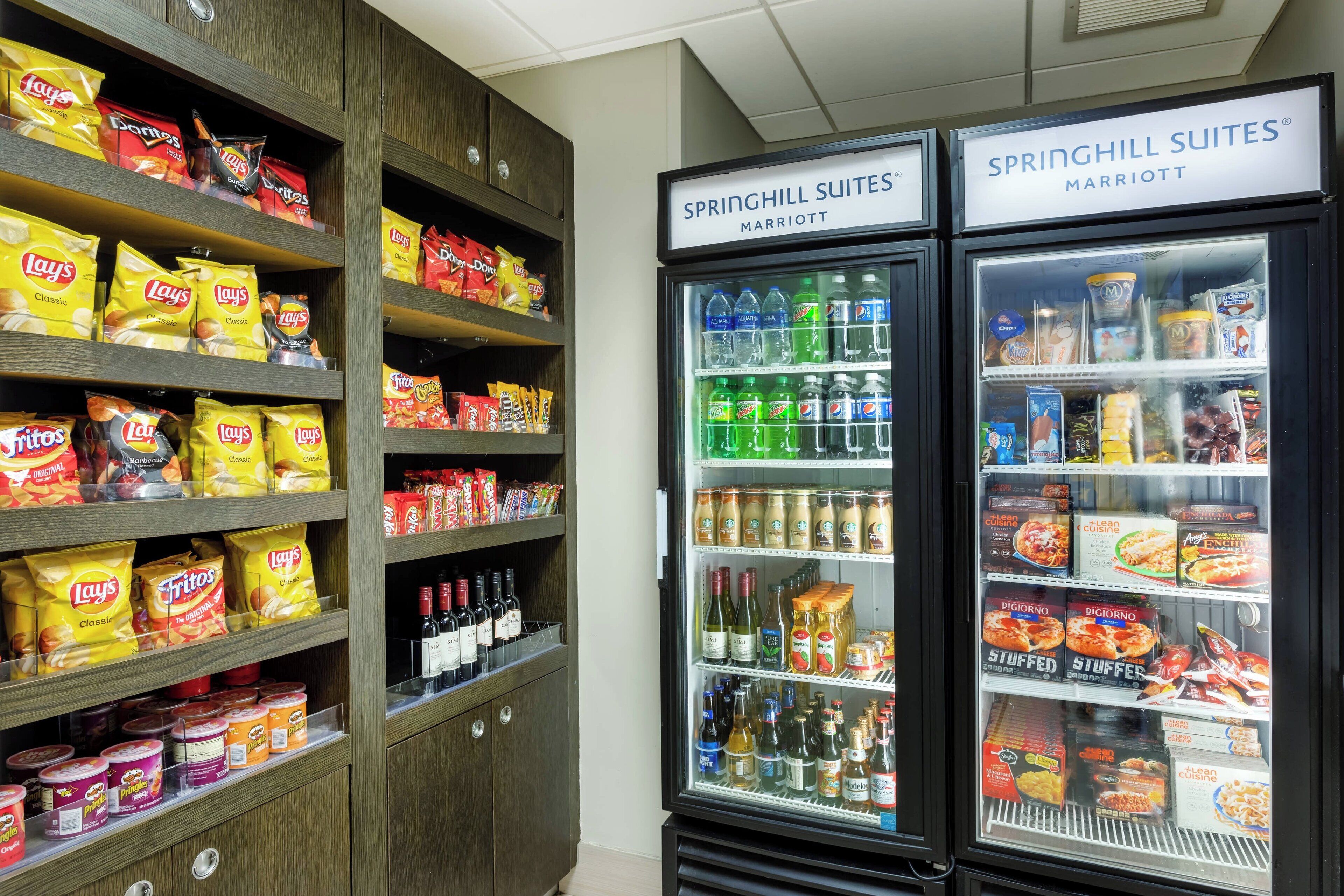 A snack and beverage refrigerator stocked with Lay's Classic and Tritos chips, and a variety of beverages including Pepsi.